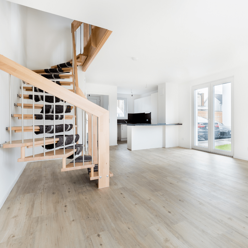 Wooden staircase in front of a kitchen in an empty apartment